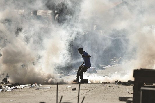 A man kicks a teargas fired by Haitian National Police during clashes in the neighbourhood of La Saline, in the Haitian capital Port-au-Prince.