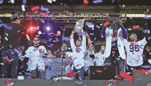 Cubsu2019 Jon Lester (34) lifts the Commissioneru2019s Trophy during the World Series victory rally in Grant Park.