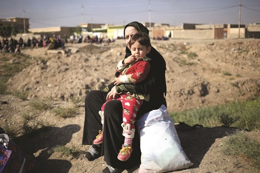 A woman who just fled the Samah district of eastern Mosul, sits with her child as she waits to board a military truck at a Iraqi special forces checkpoint in Kokjali, east of Mosul, yesterday.