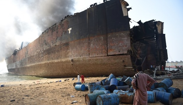 A Pakistani man looks at the wreckage of a burning ship a day after a gas cylinder explosion at the Gadani shipbreaking yard, some 50 kilometres (30 miles) west of Karachi, on November 2, 2016.