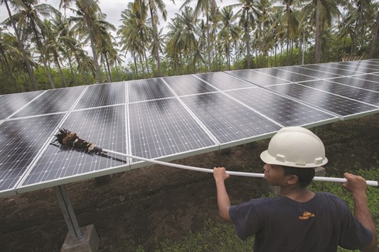 File photo shows an employee of PT Perusahaan Listrik Negara (PLN) cleaning the surface of solar panels at a solar power generation plant in Gili Meno island, Indonesia.