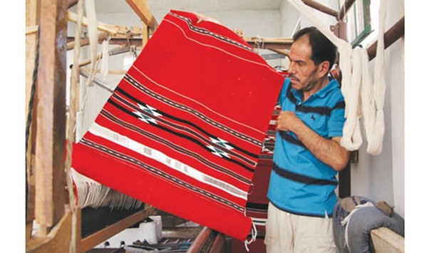 Syrian weaver Abu Mohamed displays an unfinished carpet at a workshop in the village of Ariha, on the southern outskirts of Syriau2019s rebel-held Idlib province, on the last day of weaving before the workshop was forced to close due to a lack of thread imported from conflict-ridden Aleppo. Weaving has been devastated by Syriau2019s five-year civil war, with thread becoming too difficult to procure from Aleppo - once the countryu2019s artisanal hub but now ravaged by fighting and bombardment.