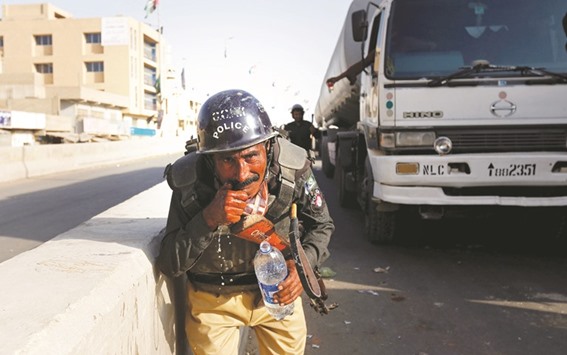 A policeman washes away the effects of tear gas fired by police after a group of men blocked the main national highway and railway tracks to protest the detention of their religious workers in Karachi yesterday.