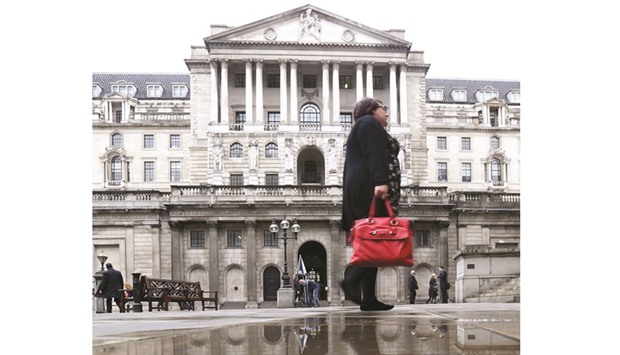 A pedestrian walks past a rain water puddle near the Bank of England in London. The BoE expects weaker business investment after the Brexit vote to represent one of the main drags on British economic growth next year, though it now expects the slowdown to be less severe than it forecast in August.