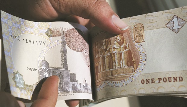 A man counts Egyptian notes outside bank in Cairo. The push to finalise the IMF loan comes as Egyptian banks began freely trading foreign exchange on the interbank market this week for the first time yesterday.