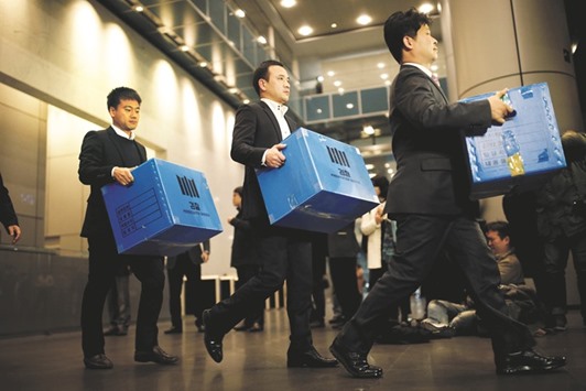 Investigation officers walk out with boxes carrying evidence seized at Samsung Electronics in Seoul yesterday.