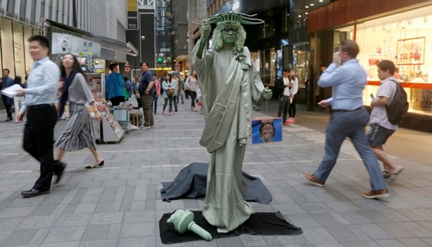 A street performer dressed as the Statue of Liberty hold photos of US presidential candidates Donald Trump and Hillary Clinton at the financial Central district in Hong Kong, China.