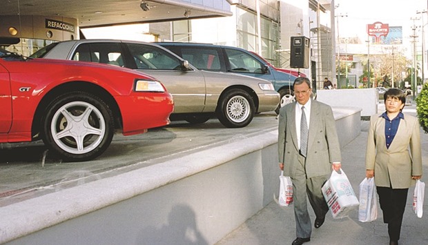 People pass by a Ford and Lincoln Dealership in Mexico City. Trump has threatened to slap a 35% tariff on any cars Ford builds in Mexico and ships back to the US. The automaker in September said it was moving small-car production from a factory in Michigan to Mexico, a move Trump attacked in the first answer of the first debate.