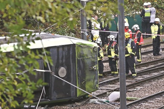 Members of the emergency services work next to a tram after it overturned injuring and trapping passengers in Croydon, south London, yesterday.