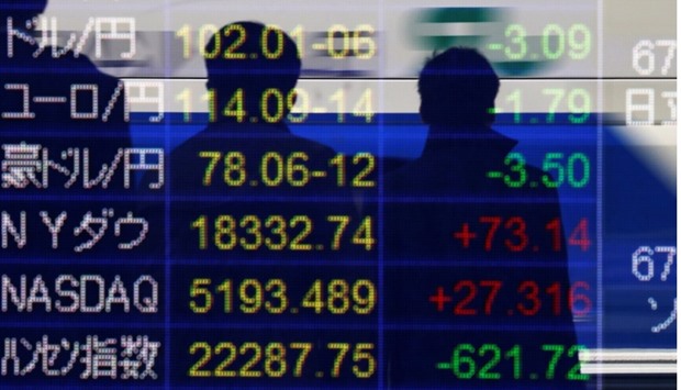 Passersby are reflected in an electronic board showing exchange rates between (from top to bottom) the Japanese yen against the US  dollar, the euro, and Australian dollar, and market indices of Dow Jones, NASDAQ, Hang Seng Index and Shanghai Composite Index outside a brokerage in Tokyo, Japan