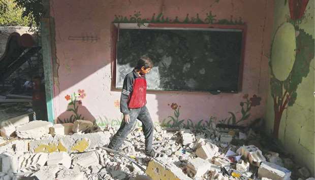 A Syrian boy walks amid the rubble inside his damaged school in the besieged rebel-held Eastern Ghouta town of Hamouria, on the outskirts of the Syrian capital Damascus.