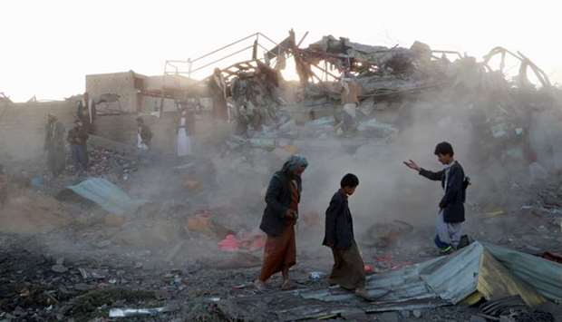 People walk at the site of an air strike in the northwestern city of Saada, Yemen