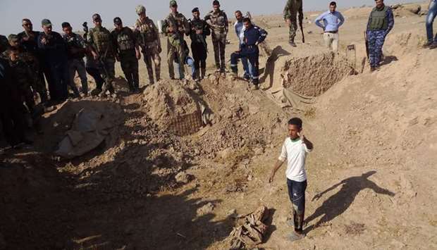 Iraqi forces search the site of a suspected mass grave containing the remains of victims of the Islamic State group