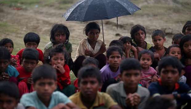 Rohingya refugee children sit in a line in the rain as they wait to receive permission from the Bangladeshi army to continue their way after crossing the Bangladesh-Myanmar border, at a port in Teknaf, Bangladesh. Reuters