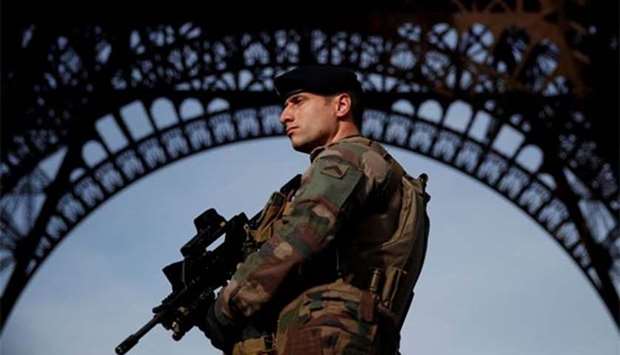 A French soldier stands guard under the Eiffel Tower. Heavily armed soldiers still patrol the streets of Paris.