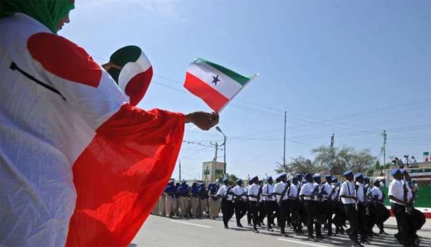 A woman waving a flag as soldiers and other military personnel of Somalia's breakaway territory of S