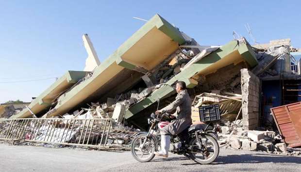 A man rides a motorcycle past a damaged building following an earthquake in the town of Darbandikhan, near the city of Sulaimaniyah, in the semi-autonomous Kurdistan region, Iraq.