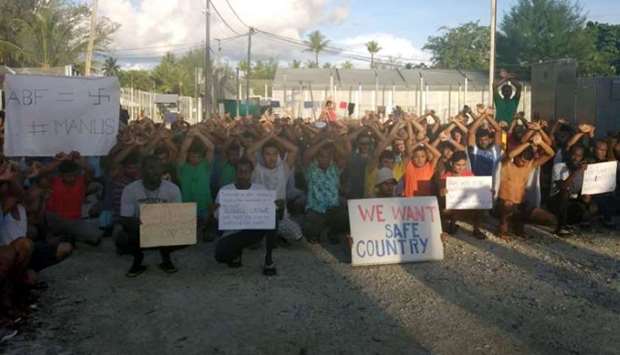 Asylum seekers hold placards in protest to moving to another centre on Manus island