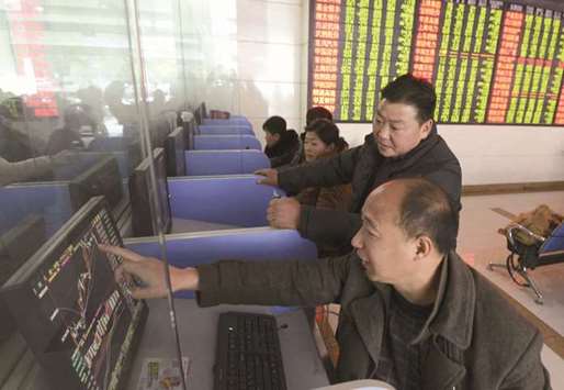 Investors talk as they look at a computer screen showing stock information at a brokerage house in Fuyang, China. Chinese shares from the mainland and Hong Kong to the US have advanced this year amid strong earnings and economic data.