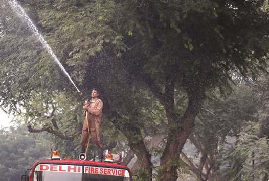 A firefighter sprays water onto trees to fight the air pollution in Delhi yesterday.