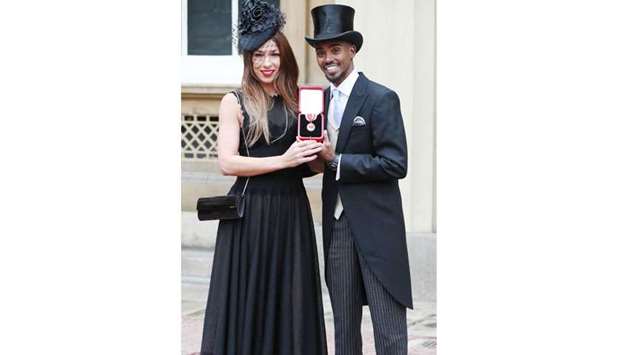 Mo Farah holds his medal as he and his wife poses for a photograph, after he was knighted during an investiture ceremony at Buckingham Palace, in London yesterday.