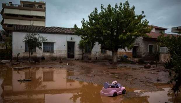 A toy car is seen in a flooded street next to a damaged house in Mandra, northwest of Athens, on Wednesday after heavy overnight rain.
