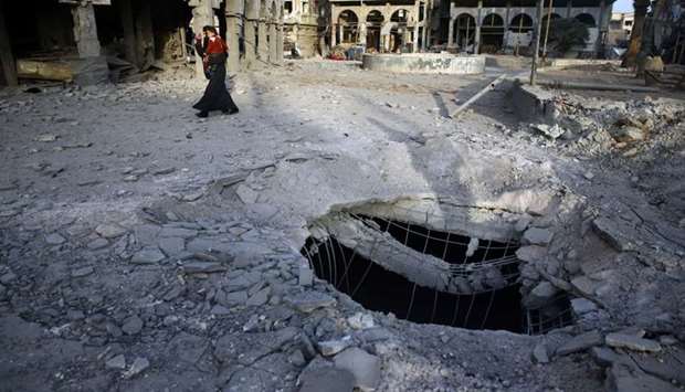 A Syrian woman walks past damaged buildings in Douma, in the eastern Damascus suburb of Ghouta, Syria.