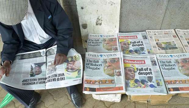 A man reads a local daily next to others with headlines about the situation in Zimababwe