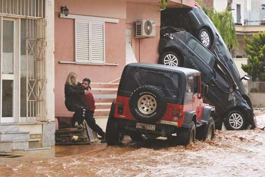 A man helps evacuate a woman from a flooded street in Mandra, northwest of Athens, yesterday.