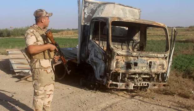 A member of the Iraqi security forces looks at the wreckage of a vehicle as troops gather in the Rawa area during an operation to retake the Euphrates Valley town from the Islamic State.