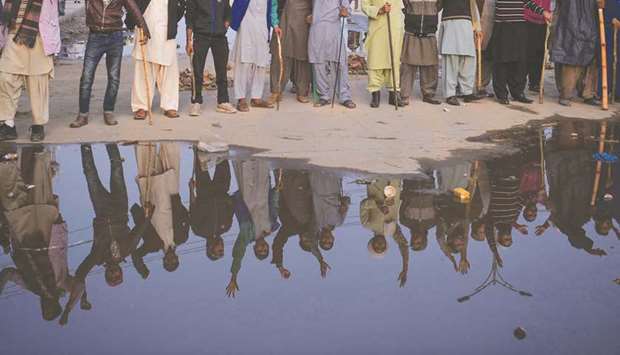 Tehreek-e-Labaik Pakistan members are seen reflected yesterday on a puddle near the blocked highway leading into Islamabad.
