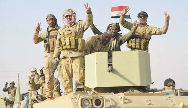 Iraqi forces show victory signs after they captured Rawa, the last remaining town under Islamic State control, yesterday.