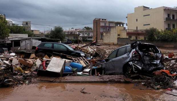 Destroyed cars are seen on a muddy street following flash floods which hit areas west of Athens