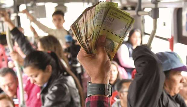 Venezuelan national Jhonger Pina, 25, sells candies and shows Bolivar bills as a curiosity to passengers, in exchange for local coins on a bus in Bogota.