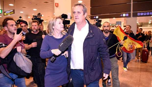 Catalan dismissed Interior chief Joaquim Forn (C) is followed by journalists as people with Spanish flags shout at him upon his arrival at El Prat airport in Barcelona after flying from Brussel.