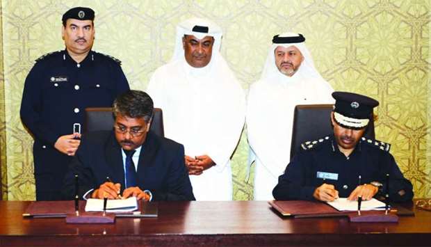 Brigadier Mohamed Ahmed al-Ateeq and Suresh Kumar, manager of the Singapore-based company, sign the agreement as other officials look on.