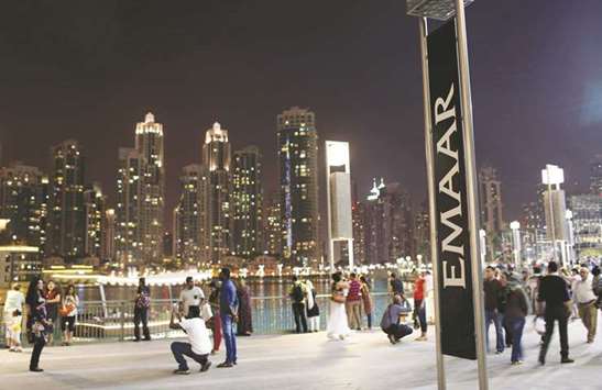 People have their pictures taken near an Emaar sign outside the Dubai Mall in the UAE. Advisers to Emaar Properties scrambled to complete a $1.3bn offering in its UAE development business after local investors reneged on hundreds of millions of dollars in demand on the last day of the sale.