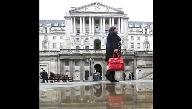A pedestrian walks past a rain water puddle near the Bank of England in London. The BoE policymakers are forecast to vote to increase the central banku2019s key interest rate to 0.50% from a record-low 0.25% after a regular gathering today, mirroring policy tightening seen in the US and eurozone.