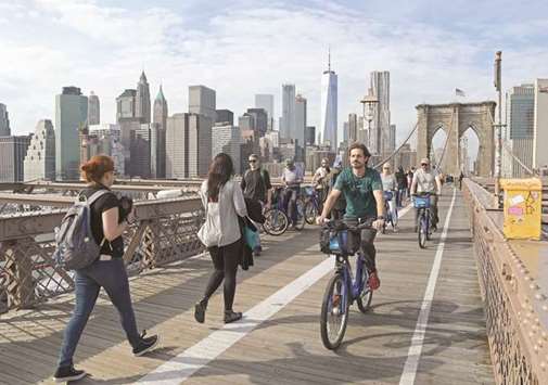 People bike on Brooklyn Bridge from downtown Manhattan in New York.