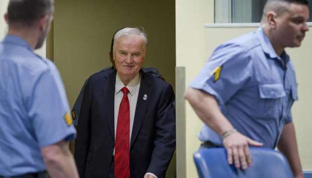 Bosnian Serb military chief Ratko Mladic (C) smiles as he enters the International Criminal Tribunal for the former Yugoslavia (ICTY).