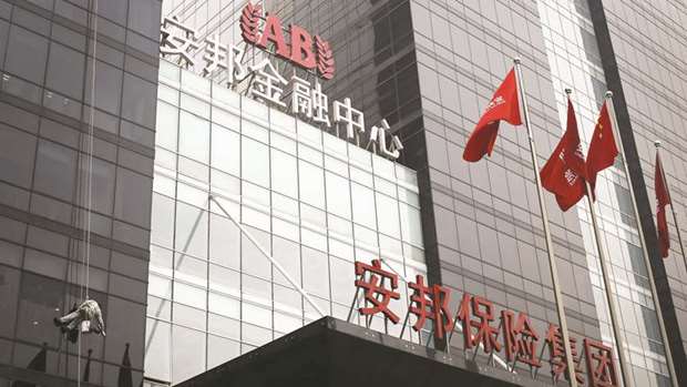 A worker cleans windows of the Anbang Insurance Groupu2019s building in Beijing. The insurer has been asked by Chinese regulators to reduce its stakes in China Minsheng Banking and China Merchants Bank to comply with new rules governing bank shareholdings, according to people familiar with the matter.