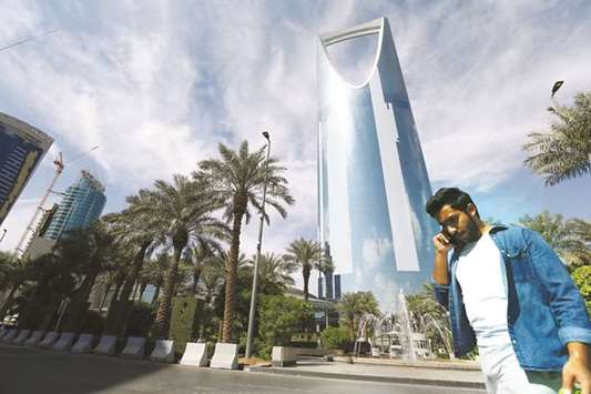 A man speaks on the phone as he walks past the Kingdom Centre Tower in Riyadh (file). Several family groups and businessmen who arenu2019t implicated in the purge are talking to local banks and international law firms about how to structure their companies to make it harder for the kingdom to confiscate or seize assets.