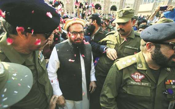 Hafiz Saeed is showered with flower petals as he walks to court in Lahore yesterday.