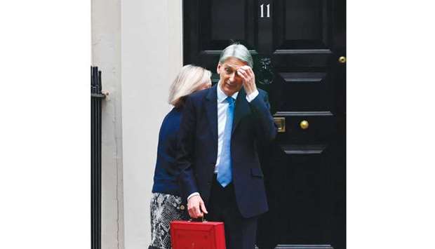 Chancellor of the Exchequer Philip Hammond scratches his head as he waits for his ministerial team to depart before posing with the Budget Box as he leaves 11 Downing Street in London yesterday.