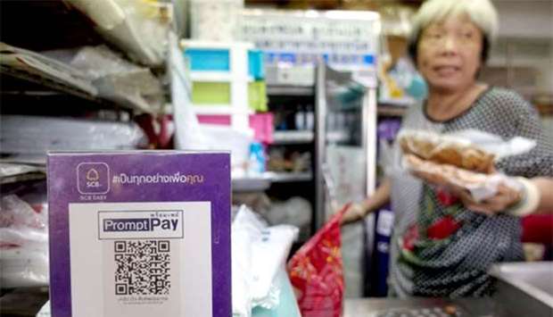 An advertisement board displaying a QR code is seen as a vendor works at a market in Bangkok.