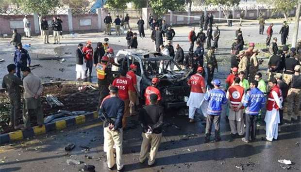 Pakistani security personnel inspect a destroyed vehicle at the site of suicide bomb attack that targeted a senior police officer in Peshawar on Friday.