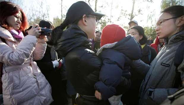 A parent is surrounded by members of the media outside the kindergarten run by preschool operator RYB Education Inc being investigated by China's police, in Beijing on Friday.