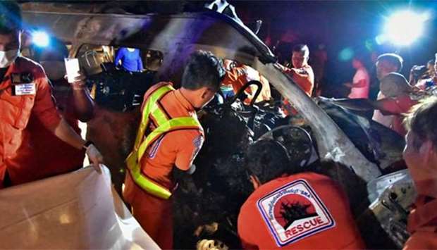 Thai rescue workers inspecting the aftermath of a van collision which killed a Thai van driver and 13 Burmese passengers in the central Thai province of Singburi.