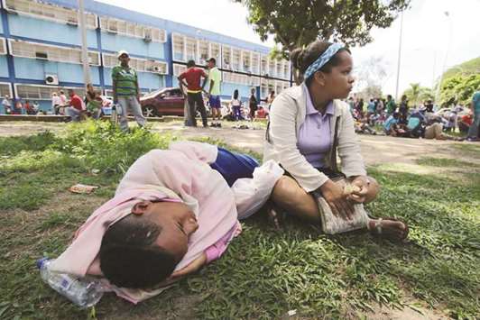 People lay on the grass outside a health center as they wait to get treatment for malaria, in San Felix, Venezuela November 3, 2017.