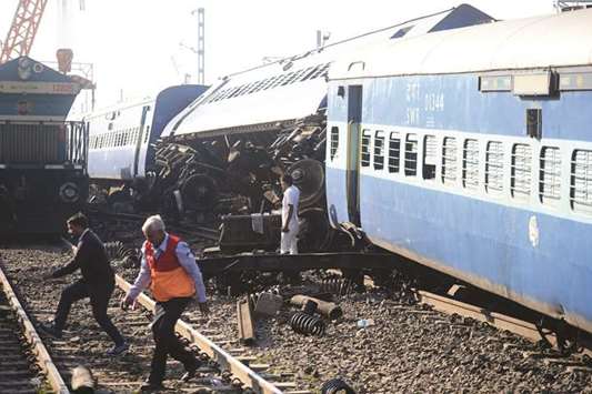 People stand near the derailed coaches of the express train near Manikpur railway station in Uttar Pradesh.